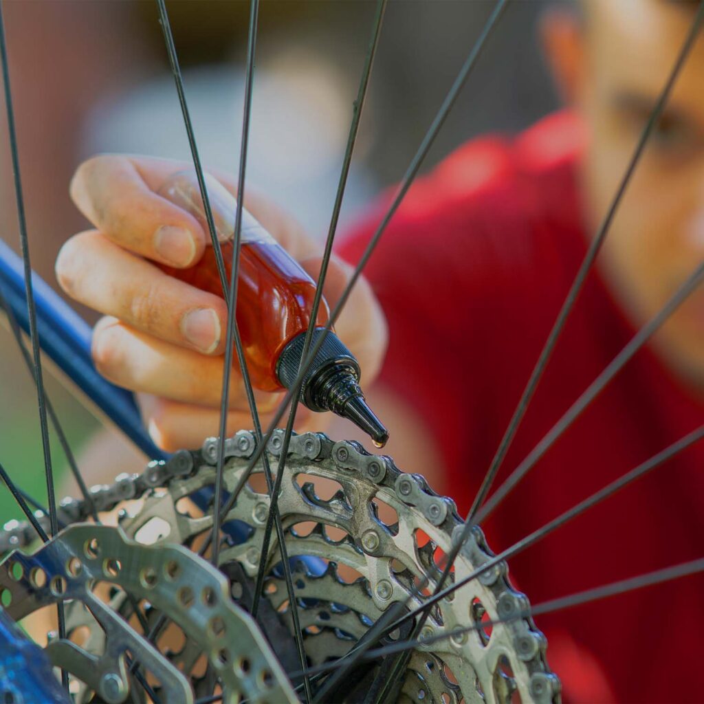 Technician applying lubricant to a bicycle cassette during drivetrain maintenance at eMotoX Sports