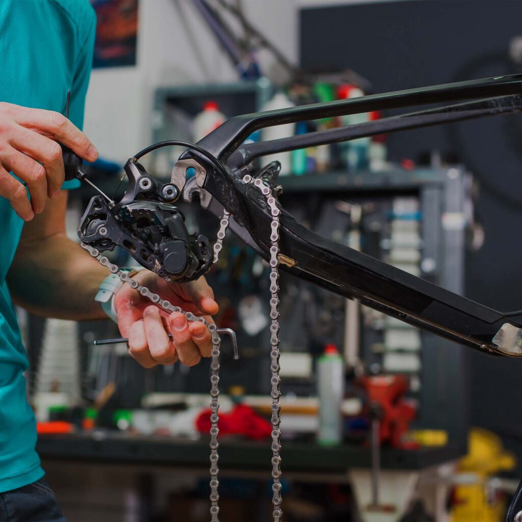 Technician performing a full drivetrain and derailleur overhaul on a bicycle at eMotoX Sports